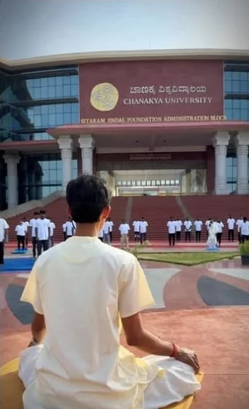 Shrungar seated facing Chanakya University, with students standing in rows in front of the building